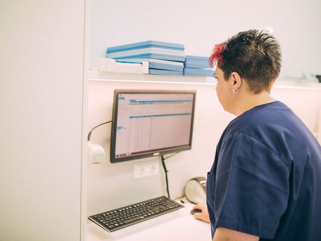 Zahnarzthelferin überträgt Patientendaten in einen Computer.
