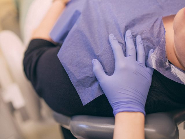 Zahnarzthelferin legt Hand auf die Schulter von Patienten, um ihn zu beruhigen.